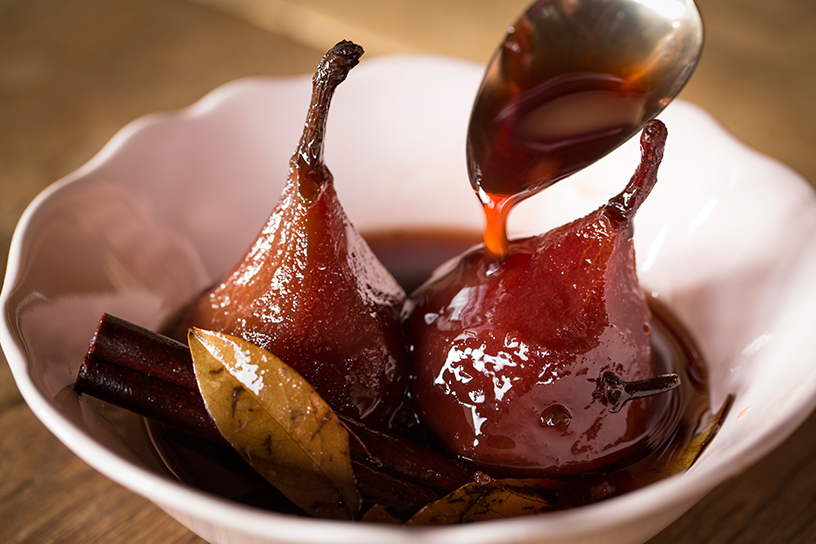 Er wordt rode wijn over stoofperen in een schaaltje gegoten